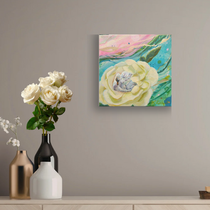 A square canvas wall art print featuring an abstract painting of a large cream-colored flower with green and pink brushstrokes, displayed on a gray wall above a console table with decorative vases and white roses.