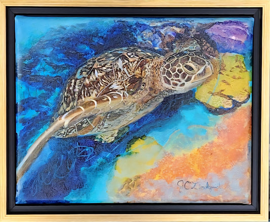 A framed mixed-media oil painting of a sea turtle swimming underwater, featuring vibrant blues, oranges, yellows, and purples, housed in a light brushed gold frame with a black inner border.